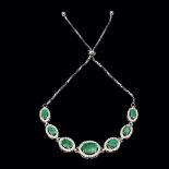 A 925 silver adjustable bracelet set with oval cut emeralds and white stones.