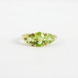 A 9ct yellow gold ring set with oval and trillion cut peridots, (I.5).