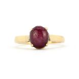 A yellow metal (tested high carat gold) solitaire ring set with a cabochon cut star ruby, (J.5)
