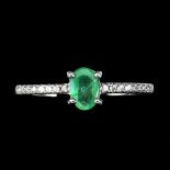 A 925 silver ring set with an oval cut emerald and white stone set shoulders, (N).