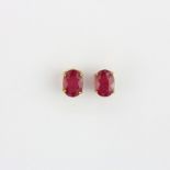 A matching pair of 9ct yellow gold stud earrings set with an oval cut ruby, L. 0.8cm.