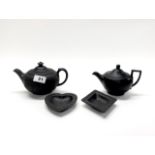 Two Wedgwood Black Basalt teapots, c. 1900, together with two Black Basalt dishes.