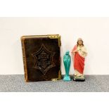 A large Victorian brass bound leather bible and two religious figures.