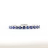 An 18ct white gold half eternity ring set with round cut sapphires, (O).