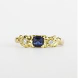 A hallmarked 18ct yellow gold ring set with a princess cut sapphire and diamonds, (R ).