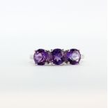 A 9ct white gold (stamped 10k) ring set with three round cut amethysts, (Q).