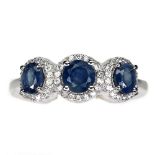 A 925 silver ring set with three round cut sapphires surrounded by white stones, (Q).