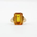A 9ct yellow gold solitaire ring set with a large baguette cut orange sapphire, (M).