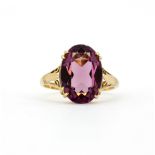 A 9ct yellow gold solitaire ring set with a large oval cut synthetic amethyst, (N.5).