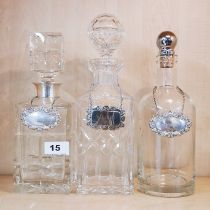 A hallmarked silver collar square cut crystal decanter with two further decanters and two hallmarked