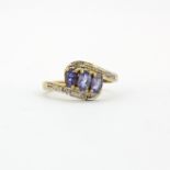 A hallmarked 9ct yellow gold crossover ring set with oval cut tanzanites and diamonds, (P).