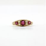 A hallmarked 9ct yellow gold ring set with an oval and round cut rubies and brilliant cut