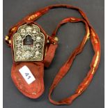 A Tibetan copper Ga'u (portable shrine) with white metal front and silk carrying case containing a