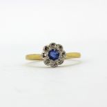 An 18ct gold and platinum daisy cluster ring set with a round cut sapphire surrounded by