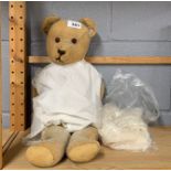 A vintage articulated teddy bear with a christening gown.