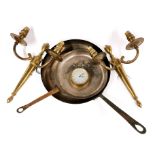 Two copper and brass frying pans, a pair of brass wall lights and a small brass clock.
