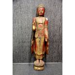 A Thai painted carved wooden figure of a standing Buddha, H. 103cm (A/F to two fingers).