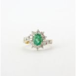 An 18ct yellow and white gold ring set with an oval cut emerald and brilliant cut diamonds,