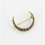 An Edwardian yellow metal (tested min. 9ct gold) crescent moon brooch set with sapphires, L. 2.8cm.