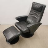 A black leather uphostered rotating, reclining armchair and footstool, H. 104cm.