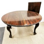 An extendable 1920's carved mahogany oval dining table with ball and claw feet and leaf. Without
