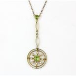 An early 20th century yellow metal (tested 15ct gold) peridot and pearl set pendant, on a 9ct gold