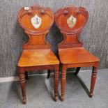 A pair of early carved mahogany hall chairs with hand painted decoration, H. 85cm.