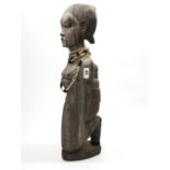 A large old, bleached, figured ebony tribal figure of a woman and child, H. 61cm, with bone bead