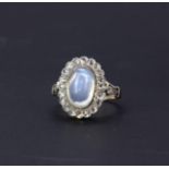 A yellow metal (tested minimum 9ct gold) cluster ring set with a large oval cabochon cut moonstone