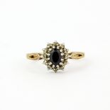 A hallmarked 9ct yellow and white gold cluster ring set with an oval cut sapphire surrounded by