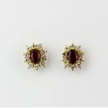 A pair of 18ct yellow gold cluster stud earrings set with an oval cut ruby surrounded by brilliant