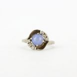 A 10ct white gold (stamped 10k) ring set with a cabochon cut star white sapphire and brilliant cut