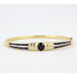 An 18ct yellow gold bangle set with sapphires and brilliant cut diamonds, 6.5 x 6cm.
