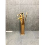 A hammered brass umbrella stand and a quantity of walking sticks.