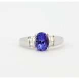 A hallmarked 18ct white gold ring set with an oval cut tanzanite and baguette cut diamond set