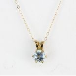 A hallmarked 9ct yellow gold pendant set with a round cut blue topaz on a 9ct yellow gold chain,