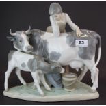 A large Lladro porcelain figure of a girl with a cow and calf, H.31cm, W. 32cm (calf tail missing).