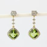 A pair of 18ct yellow gold drop earrings each set with a large curshion cut peridot and brilliant