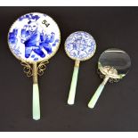 Two Chinese white metal and porcelain hand mirrors and one magnifying glass all with jade handles,