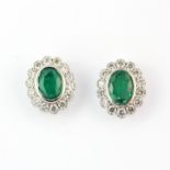 A large pair of 18ct white gold cluster stud earrings each set with an oval cut emerald, approx. 1.
