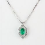 A white metal (tested high carat gold) pedant set with an oval cut emerald, approx. 0.79ct,