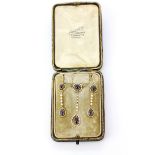An Edwardian set of yellow metal (tested minimum 9ct gold) necklace and drop earrings set with