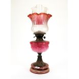 A 19th century oil lamp with pink opaline glass well, cranberry frilled shade and ceramic base, H.