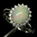 A 925 silver cluster ring set with a cabochon cut opal surrounded by white stones, (O.5).