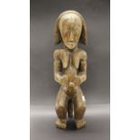 An African carved wooden tribal figure or relics guardian with applied brass eyes and belly