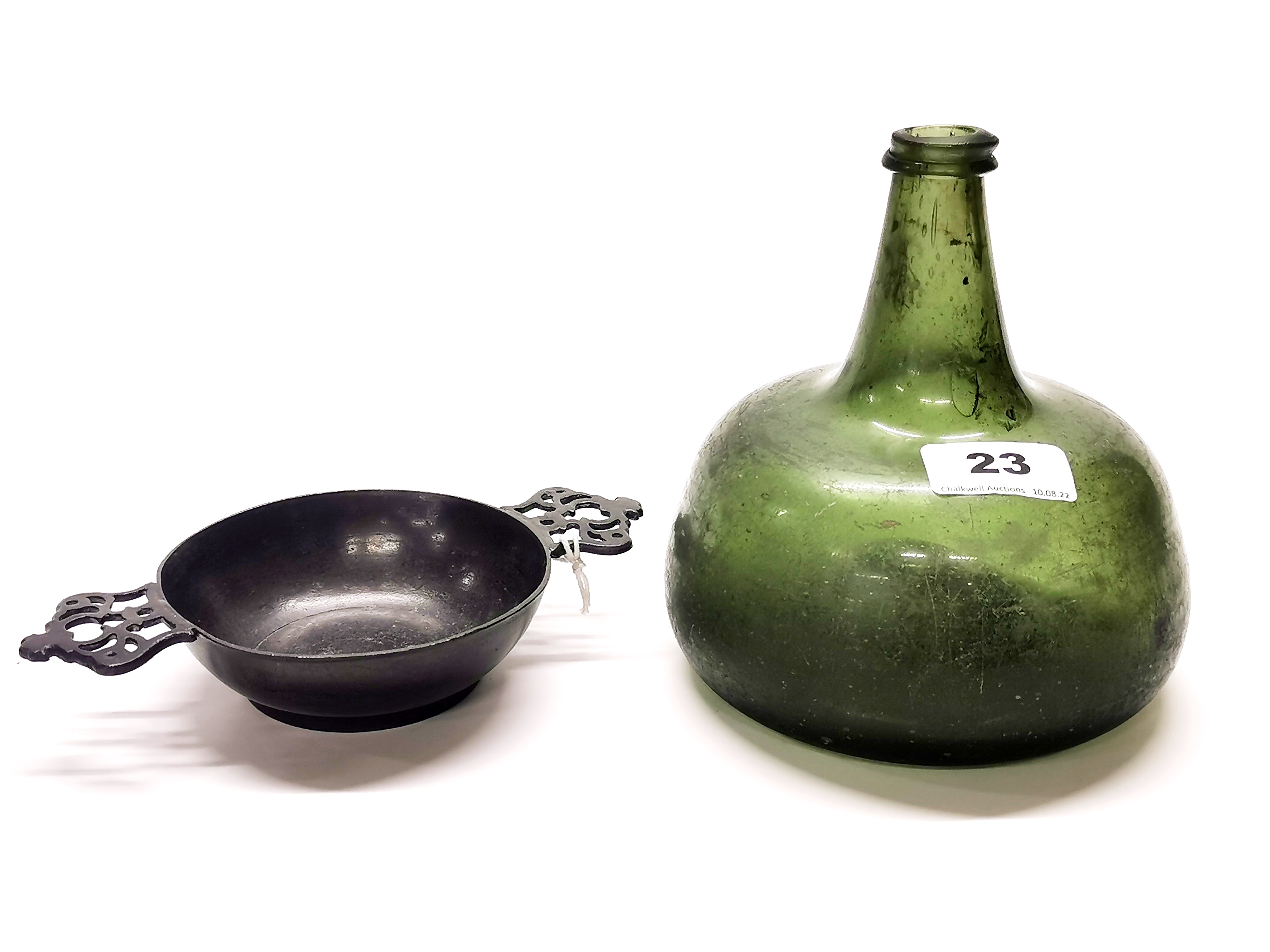 A Medieval green glass bottle, H. 16cm, together with an 18th century pewter porringer. Prov. Estate