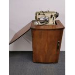 An oak crafts cabinet containing a Bernina Favorit sewing machine, 82 x 53cm.