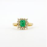 An 18ct yellow gold (stamped 18K) ring set with a square cut emerald surrounded by brilliant cut