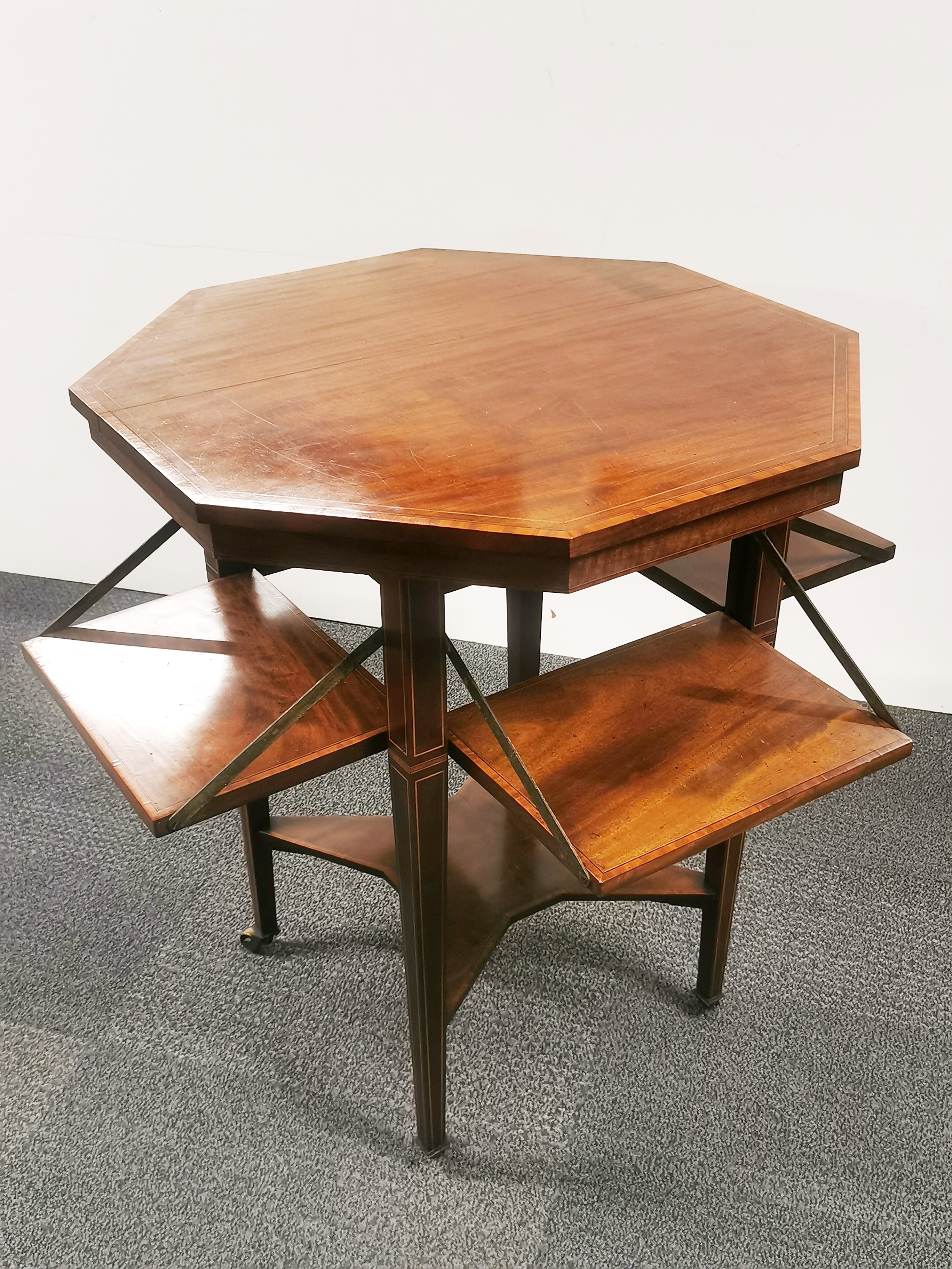 An Edwardian mahogany veneered and inlaid octagonal two-tier table with four interesting fold out