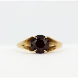 A hallmarked 9ct yellow gold solitaire ring set with a round cut garnet, (P.5).